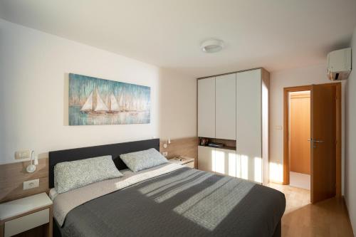 a bedroom with a bed and a painting on the wall at Humagum Sea View Apartment - Garden Palace Umag in Umag