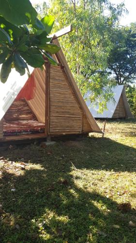 ein kleines Haus mit einem Dach auf dem Rasen in der Unterkunft Camping Ojo de Agua in Nagarote