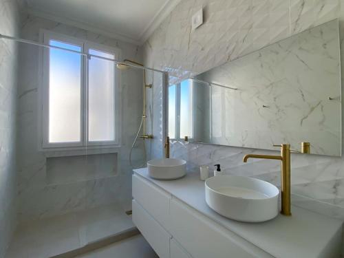 une salle de bain blanche avec deux lavabos et un miroir dans l'établissement Appartement Centre Cannes, à Cannes