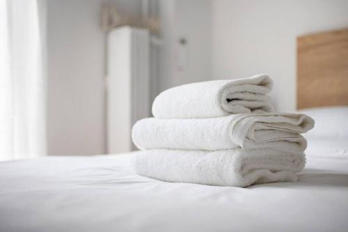 a stack of towels sitting on top of a bed at A modern apartment in the heart of Athens in Athens