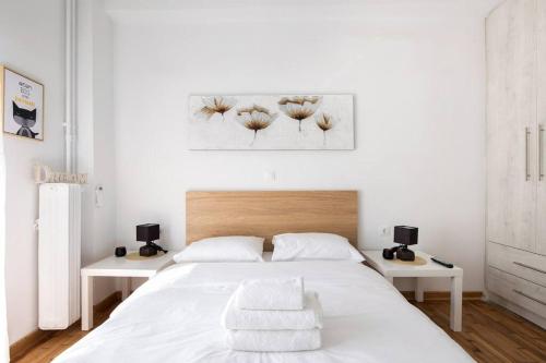 sypialnia z białym łóżkiem z dwoma białymi stołami w obiekcie A modern apartment in the heart of Athens w Atenach