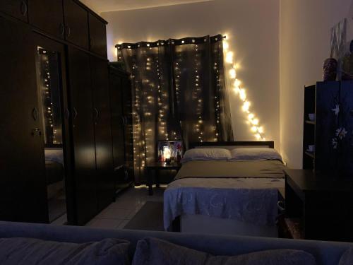 a bedroom with two beds and a curtain with lights at Studio Apartment in Sharjah