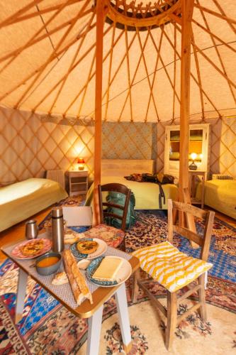 a room with a table and chairs in a yurt at Yourte - Camping des trois rivières in Bassignac