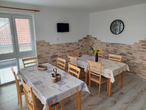 a dining room with tables and chairs and a clock at Penzion MAYKA in Hrabušice