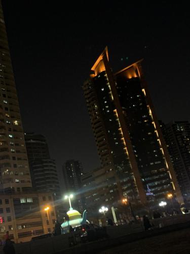 a city lit up at night with tall buildings at Studio Apartment in Sharjah