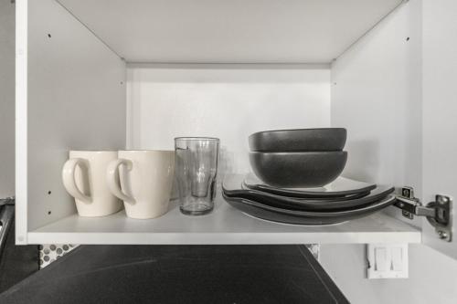 a shelf with plates and cups and a glass at Cozy 2-Bedroom Basement Suite Retreat Calgary in Calgary