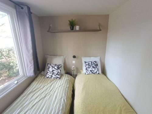 two beds in a small room with a window at Mobil-home, 3 ch , 6 personnes in Le Pont Legé