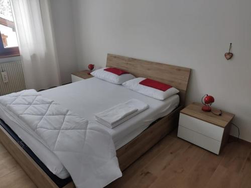 1 dormitorio con 1 cama con sábanas blancas y almohadas rojas en Falcade Dolomiti La Quiete piano terra, en Fregona