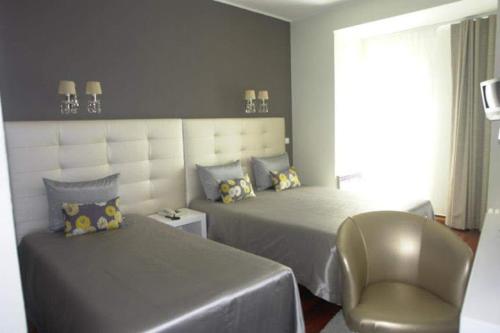 a bedroom with a large bed and a chair at Rio Maior Hotel in Rio Maior