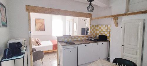 a room with a kitchen and a bedroom with a bed at Le Lamourguier in Narbonne