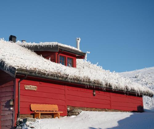 a red barn with a grass roof with snow on it at Rondane Haukliseter Fjellhotell in Høvringen