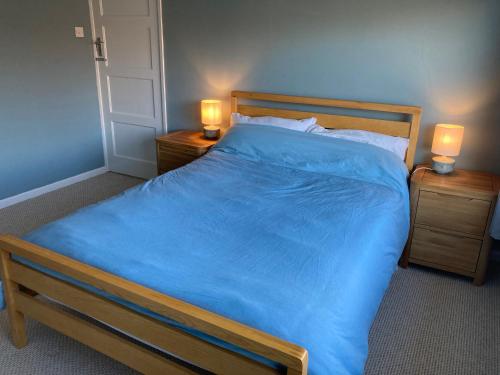 a bedroom with a large bed with blue sheets and two lamps at Cosy at Cumberland - Double room with shared bathroom in Dundonald