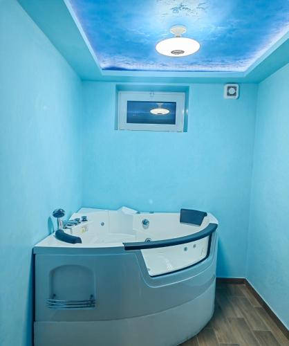 a blue bathroom with a bath tub with a ceiling at Apartman Ivica in Pančevo