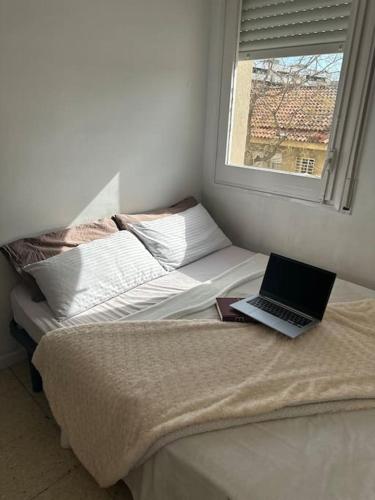 a laptop computer sitting on a bed with a window at Apartamento de 2 habitaciones Sant Andreu in Barcelona