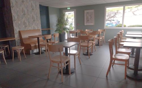 un comedor con mesas y sillas en un restaurante en B&B HOTEL Saint-Etienne Monthieu, en Saint-Étienne