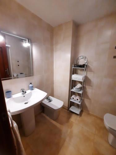 een badkamer met een wastafel, een toilet en een spiegel bij Amplio apartamento céntrico in Peñíscola