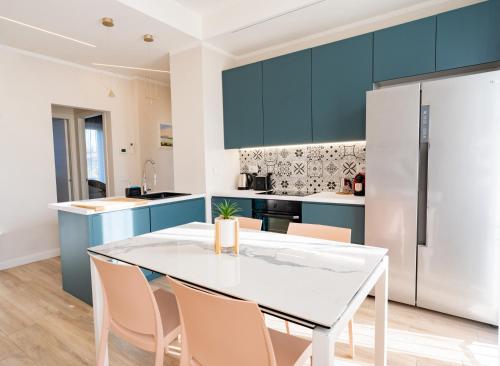 a kitchen with blue cabinets and a white table and chairs at Blu Iris - Deluxe apartment with jacuzzi in Lesa