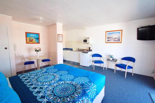 a bedroom with a bed and chairs and a kitchen at Golden Glow Motel in Rotorua