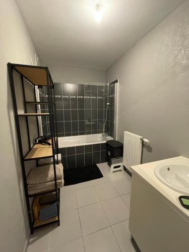 La salle de bains est pourvue d'une baignoire et d'un lavabo. dans l'établissement Appartement T3 proche centre ville, à La Teste-de-Buch