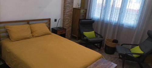 een slaapkamer met een bed en 2 stoelen bij LA BOHEME in Telde