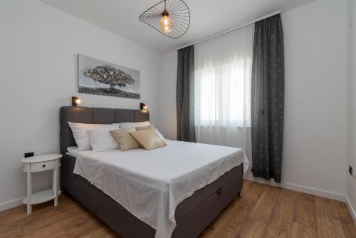 een slaapkamer met een groot bed en een raam bij Apartmani Dobrila Groundfloor II in Kaštel Novi