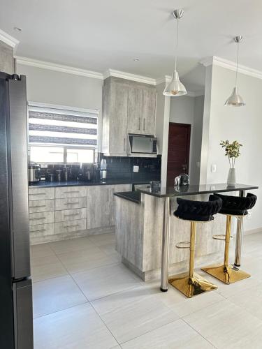 a kitchen with a black refrigerator and a counter at Get Cosy & Comfy kaZwide villa in Nelspruit
