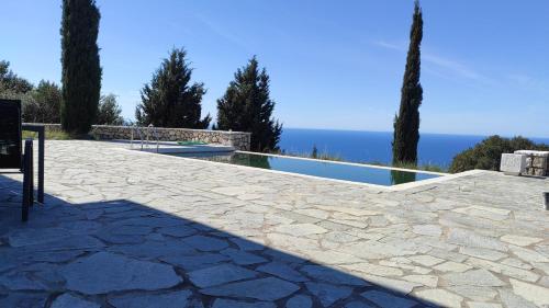 a stone patio with a swimming pool and trees at Point of View Cassiopeia in Drymon