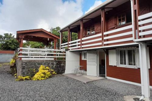 a wooden house with a porch and a patio at Chalet des laves in Sainte-Rose