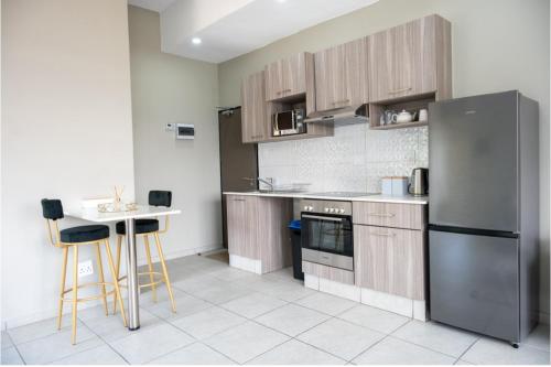 kuchnia ze stołem i lodówką ze stali nierdzewnej w obiekcie The Bolton Rosebank Apartment 26 w mieście Johannesburg