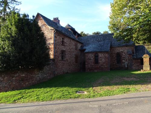 an old brick building with a grass yard next to a street at Gîte de Ségonzac in Villecomtal
