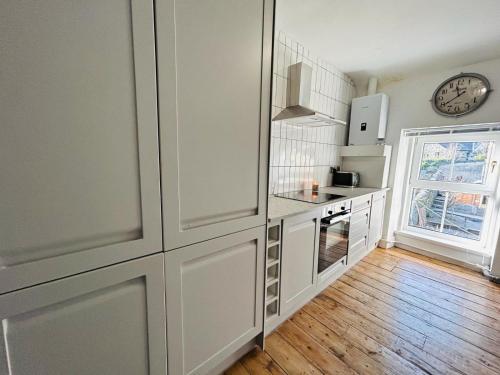 a kitchen with white cabinets and a clock on the wall at Dolgellau Grand Heights Apt in Dolgellau