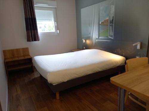 a bedroom with a bed and a table and a window at B&B HOTEL Saint-Etienne Monthieu in Saint-Étienne