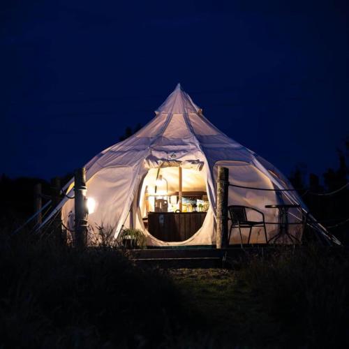 ein weißes Zelt mit einem Tisch in der Nacht in der Unterkunft Woodland View - Sleeps up to 2, double bed in Dungarvan