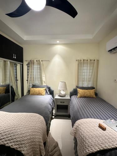 um quarto com 2 camas e uma mesa com um candeeiro em Mo's Tranquil Retreat Bliss n Jamaica em Stanmore Grove