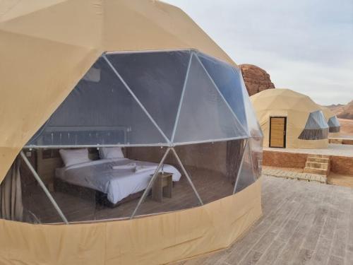 ein großes Kuppelzelt mit einem Bett darin in der Unterkunft WADl RUM DESERT CAMP in Wadi Rum
