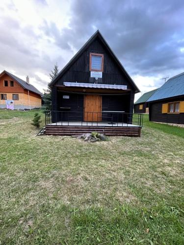 ein schwarzes Haus mit einer Veranda und einem Grasfeld in der Unterkunft Chata Dominika in Dolná Strehová