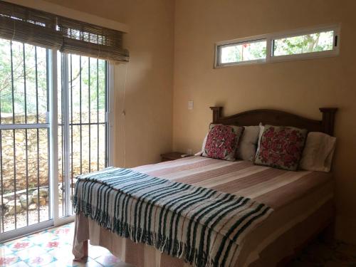 a bedroom with a large bed with two windows at Casita Amarilla in the Yellow City in Izamal