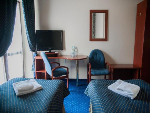 a hotel room with two beds and a table and a television at Noce i Dnie Hotel in Konstancin-Jeziorna