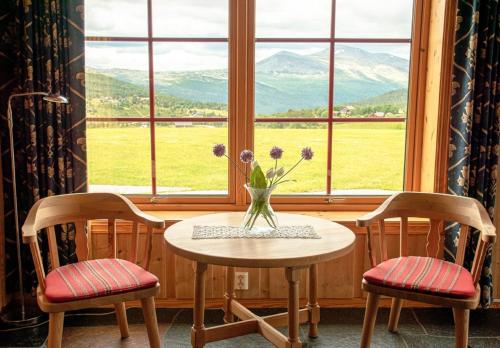 a table with two chairs and a vase with flowers at Rondane Haukliseter Fjellhotell in Høvringen