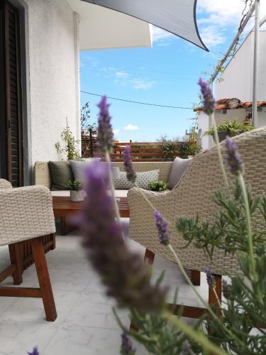 a patio with a table and chairs and purple flowers at Nord Guesthouse in Néos Pírgos