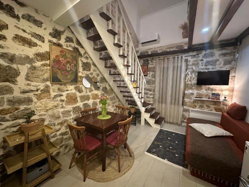 ein Wohnzimmer mit einem Tisch, Stühlen und einer Treppe in der Unterkunft Etno village Mihailovic II in Herceg-Novi