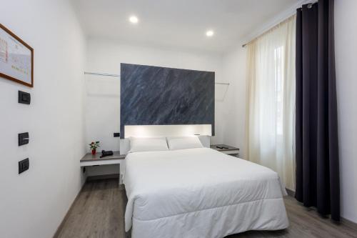 a white bedroom with a large white bed and a window at Crossroad Hotel in Rome