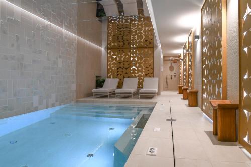 een zwembad in het midden van een kamer met stoelen bij Grand Hôtel Du Parc - Teritoria in Aix-les-Bains
