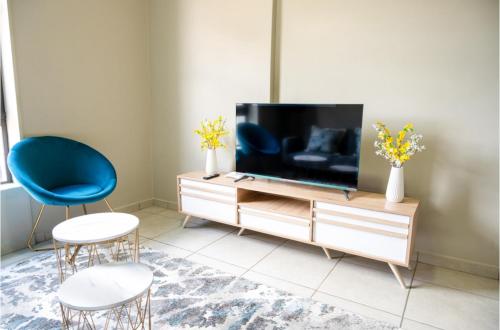 uma sala de estar com televisão e duas cadeiras em Rosebank Apartment the Bolton 27 em Joanesburgo