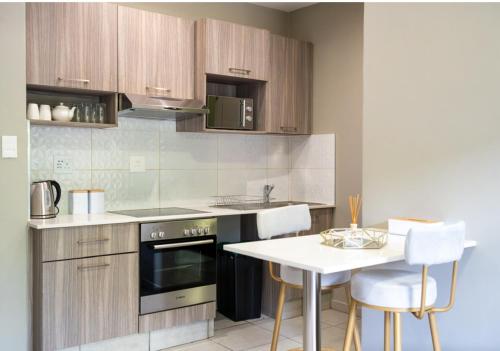 uma cozinha com um fogão e uma mesa com cadeiras em Rosebank Apartment the Bolton 27 em Joanesburgo