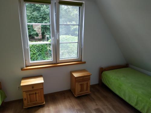 a bedroom with a green bed and a window at Domek nad jeziorem Mazury Kobyłocha 13a in Szczytno