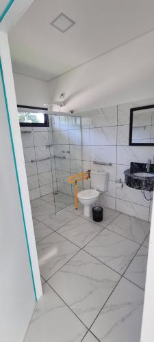 a bathroom with a toilet and a glass shower at Iguassu Jungle Hotel pousada in Foz do Iguaçu