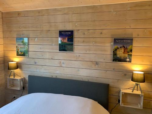 - une chambre avec des murs en bois, un lit et deux lampes dans l'établissement La Ménardière, à La Tour-Saint-Gelin