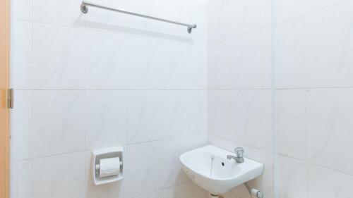 a white bathroom with a sink and a toilet at RedDoorz at Casa Buena Dormitel Davao City in Davao City