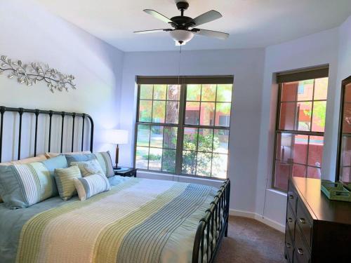 um quarto com uma cama, uma ventoinha de tecto e janelas em Sun City Grand Oasis: Luxury Condo Living in La Solana em Surprise
